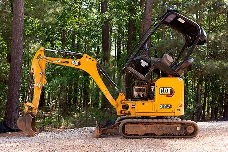 CAT 301.8 gravemaskine står ved skov med åben motorhjelm