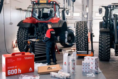 Mekaniker arbejder på Valtra traktor med Valtra service kits liggende på et bord i forgrunden